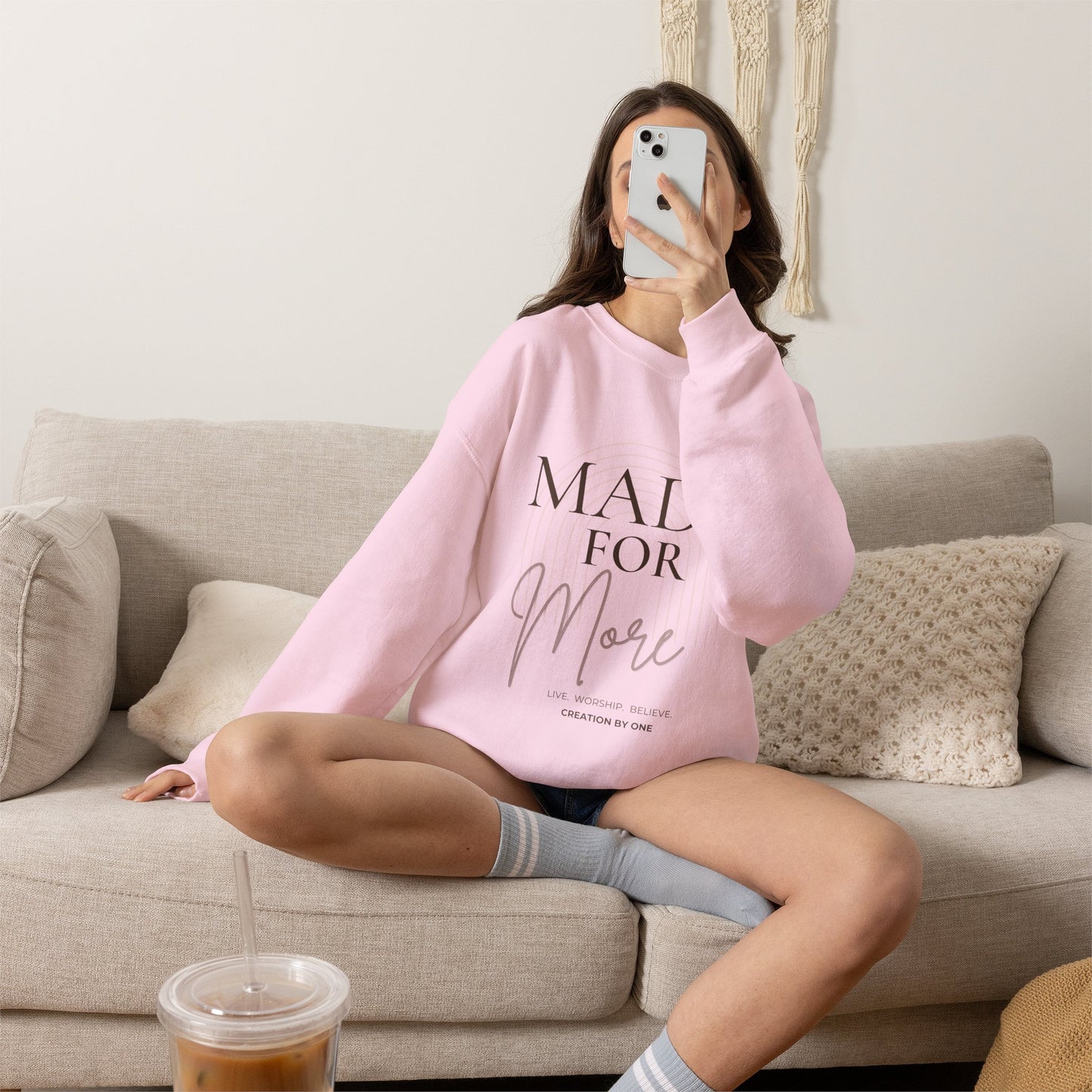 Person wearing a pink sweatshirt with 'Raising Little Readers' text, sitting on a couch.