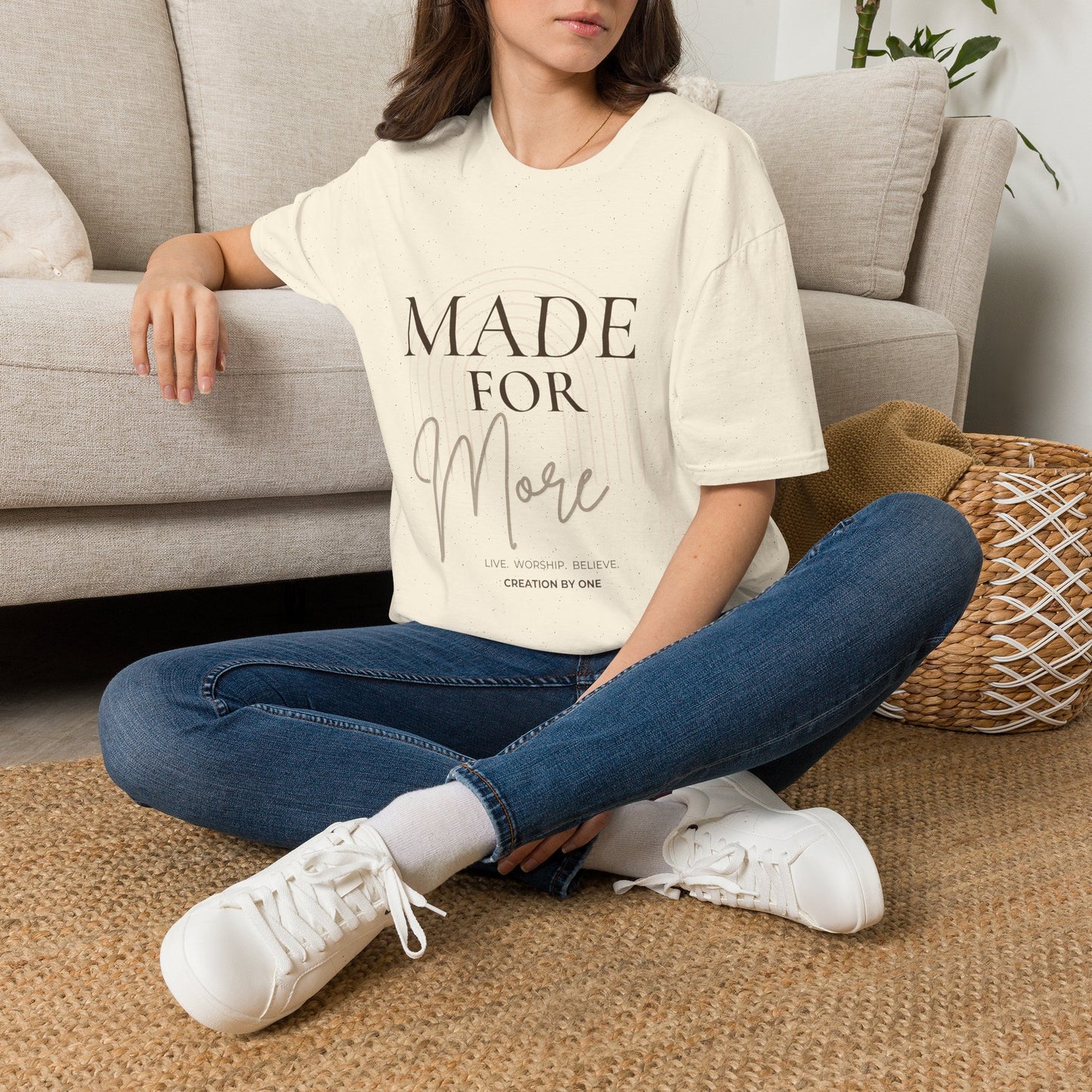 Person wearing a white t-shirt with 'Made to Worship' text, sitting on the floor in a living room.