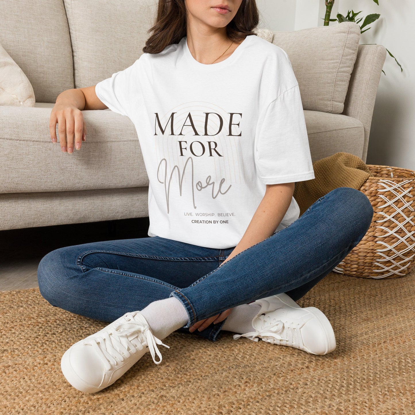 Person wearing a white t-shirt with a graphic design sitting on the floor.