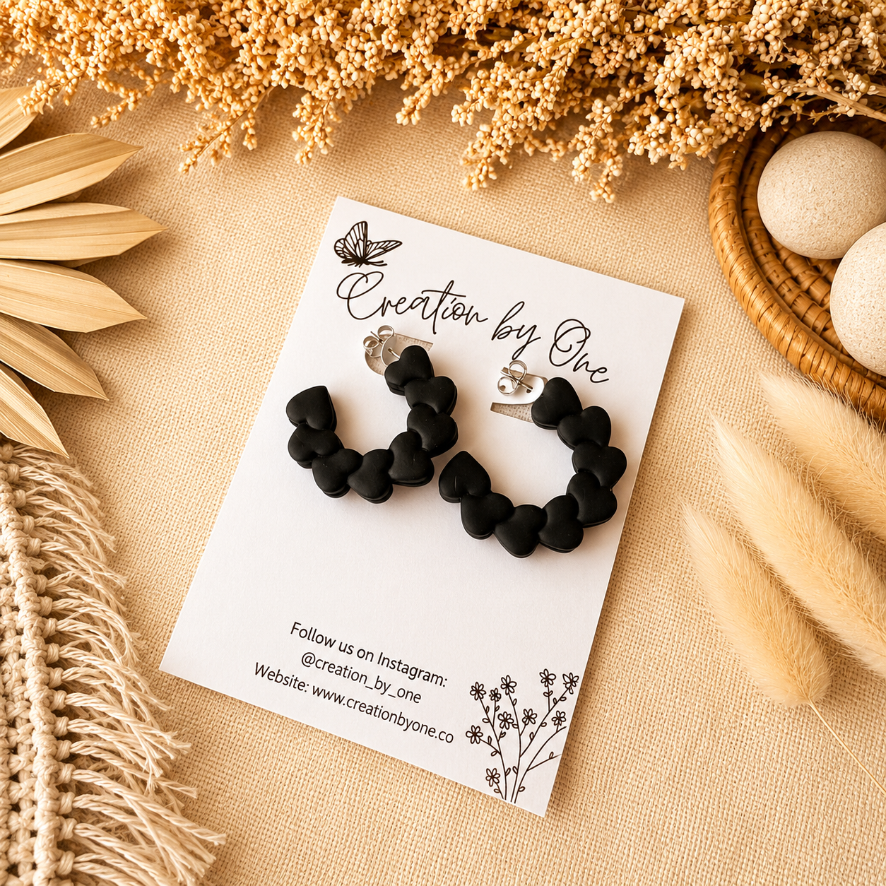 Black hoop earrings on a branded card with decorative elements on a beige surface