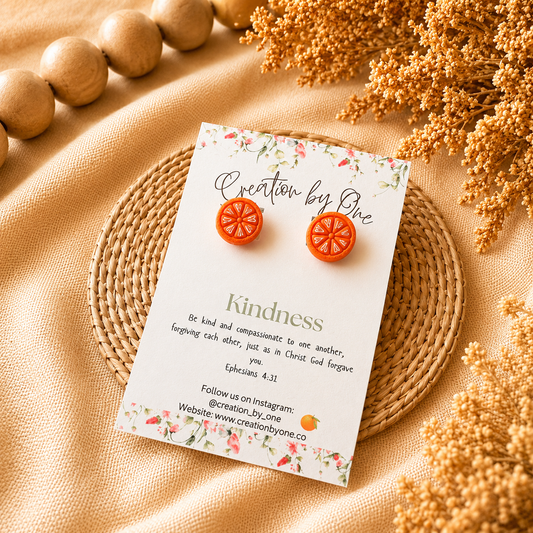 Card with orange earrings on a beige fabric background