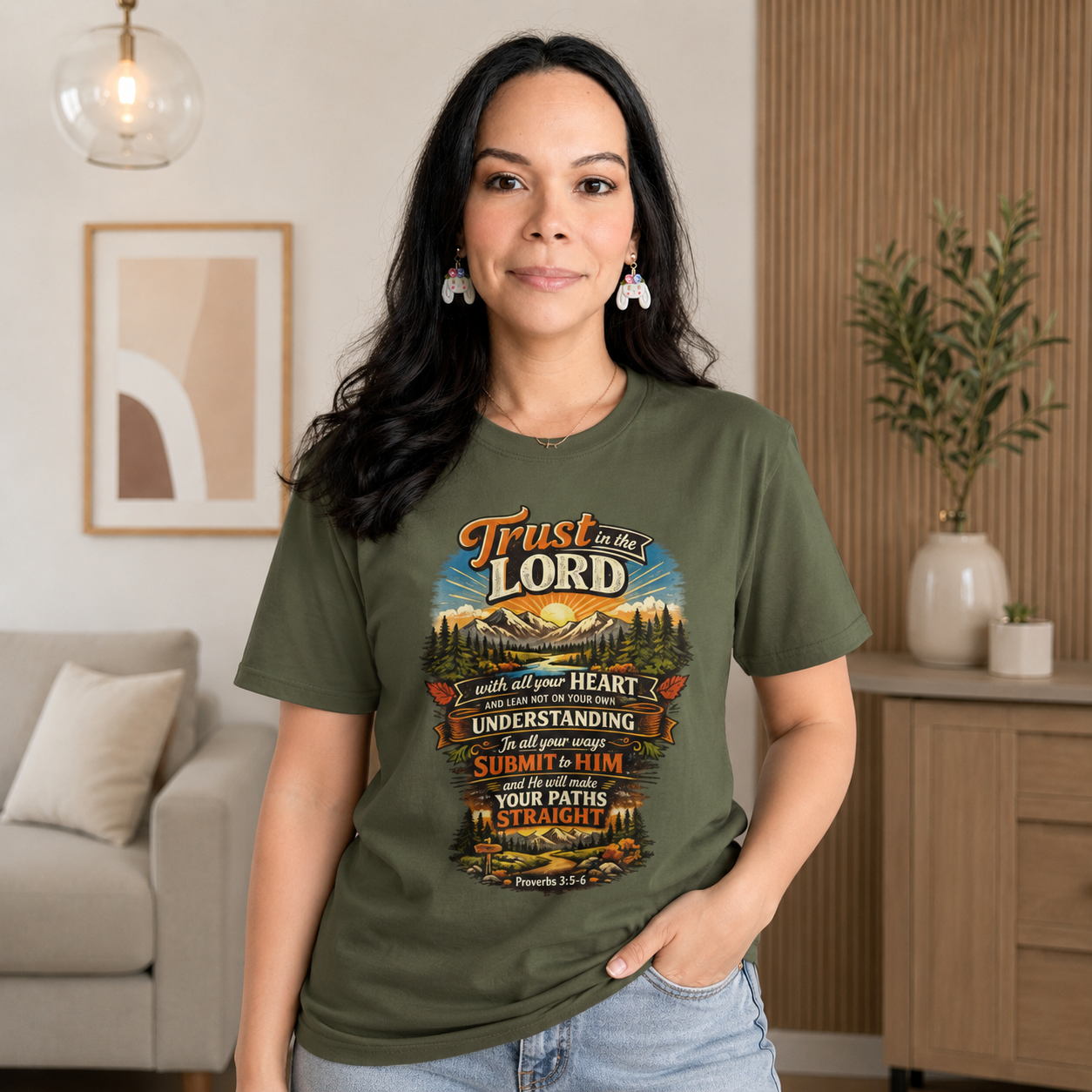 Woman wearing a cream speckled Christian graphic T-shirt featuring Proverbs 3:5–6, "Trust in the Lord," paired with light denim jeans in a bright neutral home setting. Faith-inspired lifestyle mockup by Creation by One, perfect for showcasing Christian apparel on Shopify.