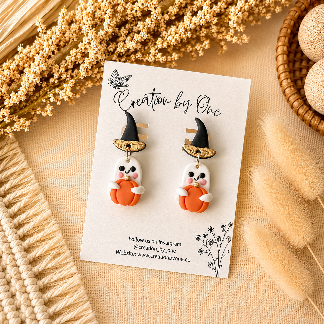 Pair of Halloween-themed earrings on a card with decorative elements on a beige surface