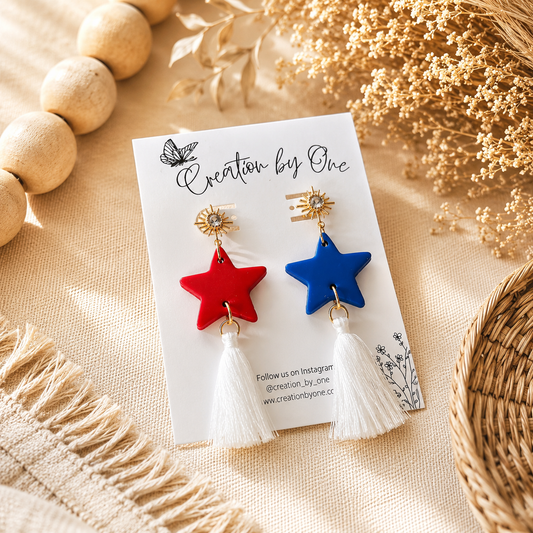 Star-shaped earrings with red and blue stars on a card labeled 'Creation by One' with decorative elements.