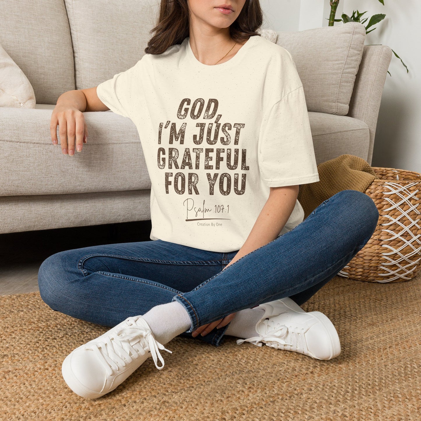 Person sitting on a carpeted floor wearing a 'Tied Up Social Club' t-shirt, blue jeans, and white sneakers.
