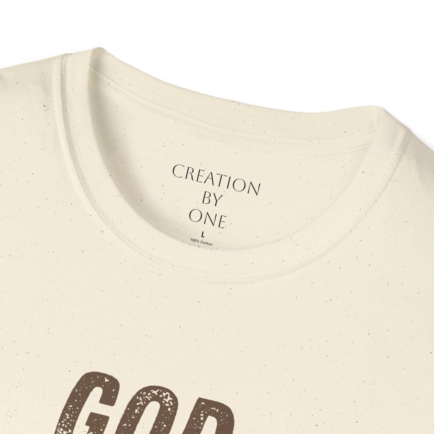 Close-up of a beige t-shirt with 'Creation by One' text on a white background