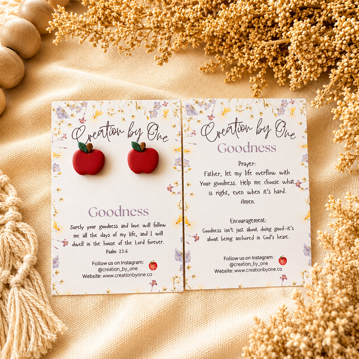 Card with red apple earrings and text on a beige fabric background