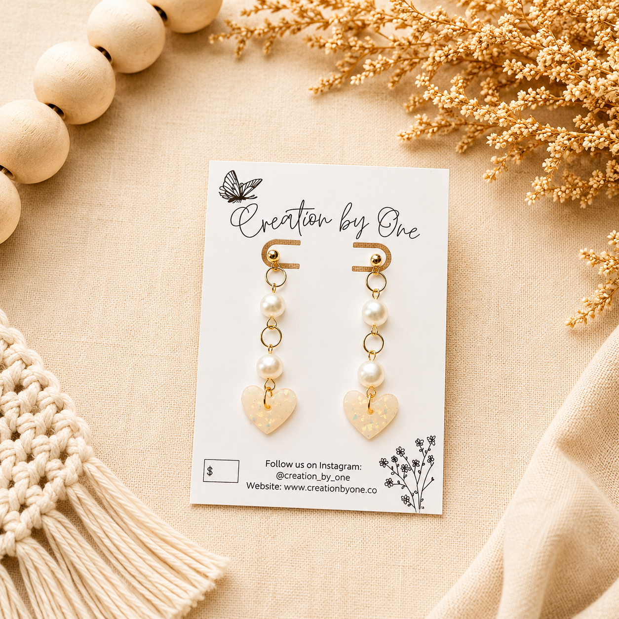 Handmade pearl and iridescent heart polymer clay dangle earrings with gold-plated studs on a neutral boho background