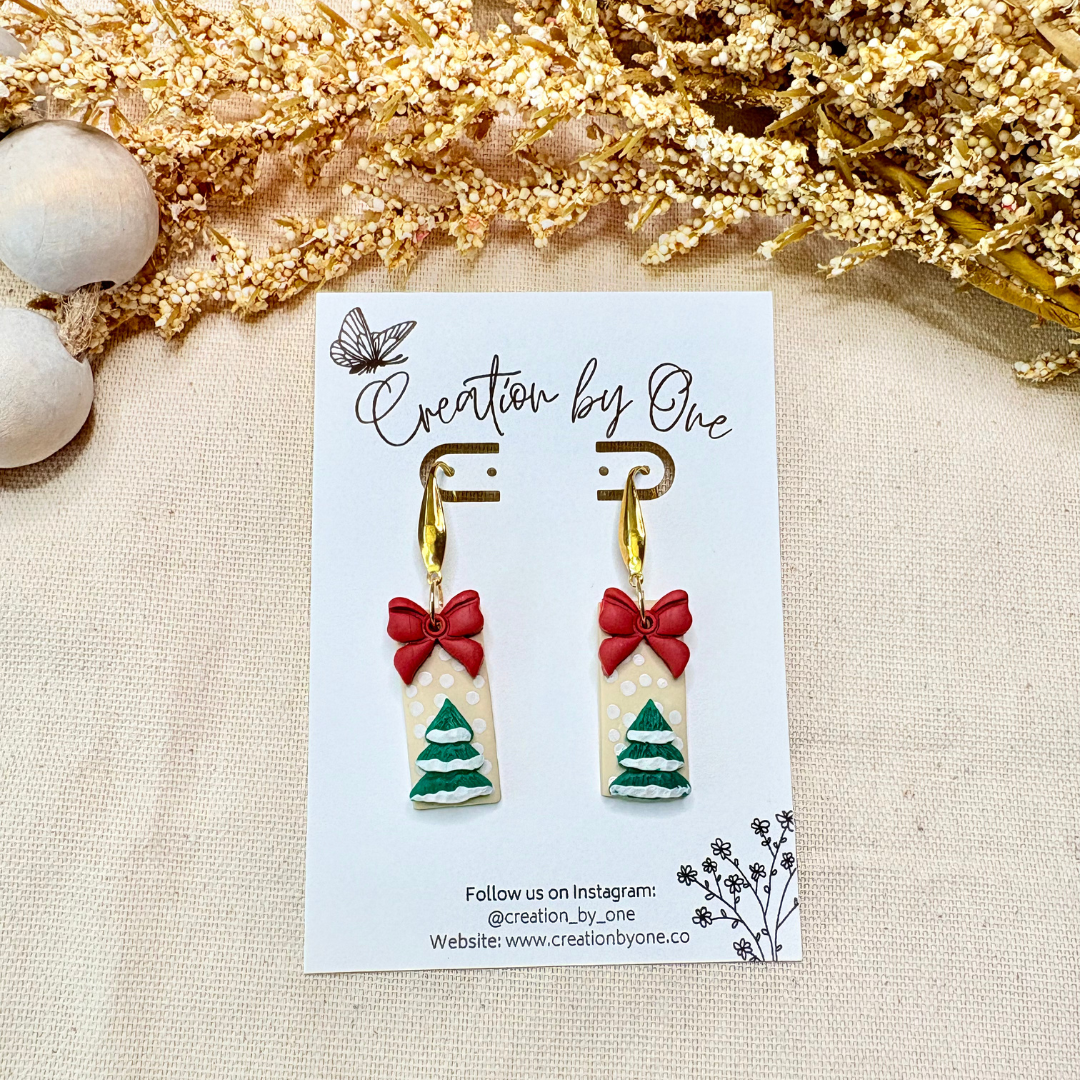 Handmade polymer clay bow earrings with 14K gold-plated hardware on snowy neutral Christmas background
