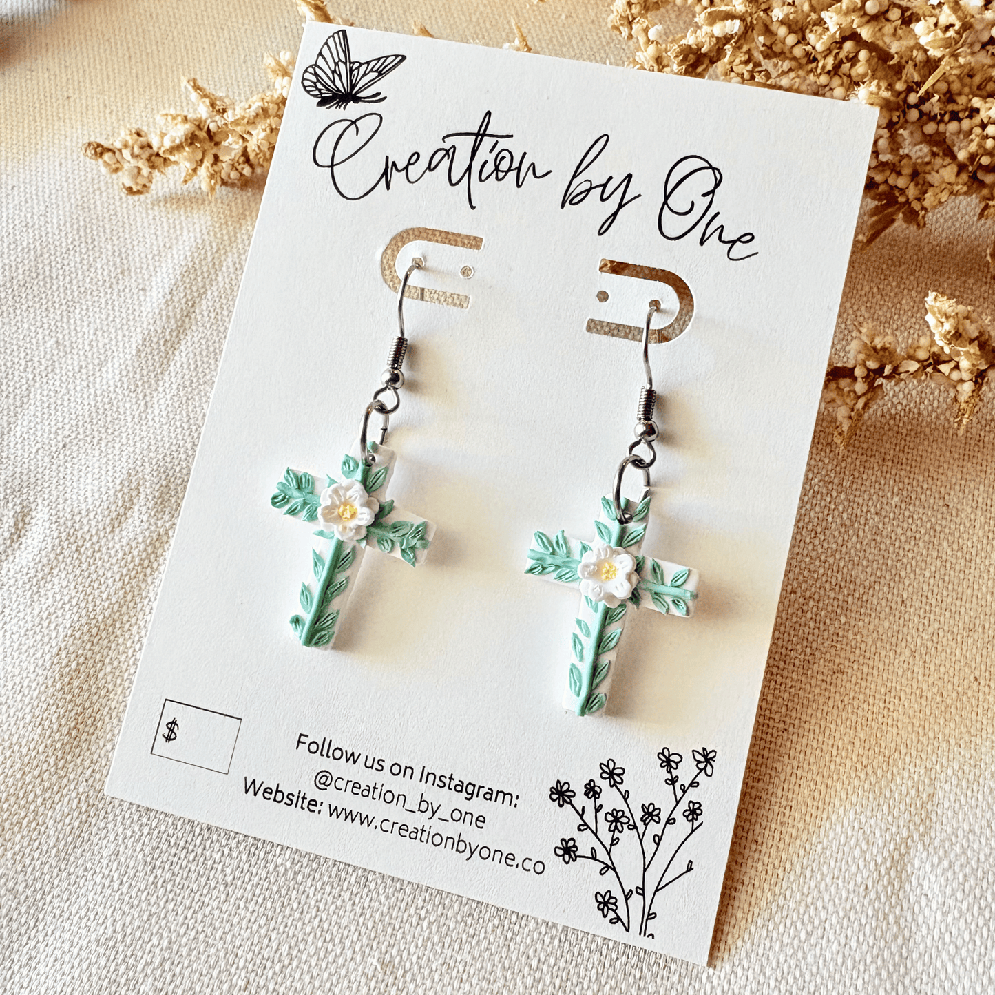 Floral earrings on a 'Creation by One' branded card with decorative elements.