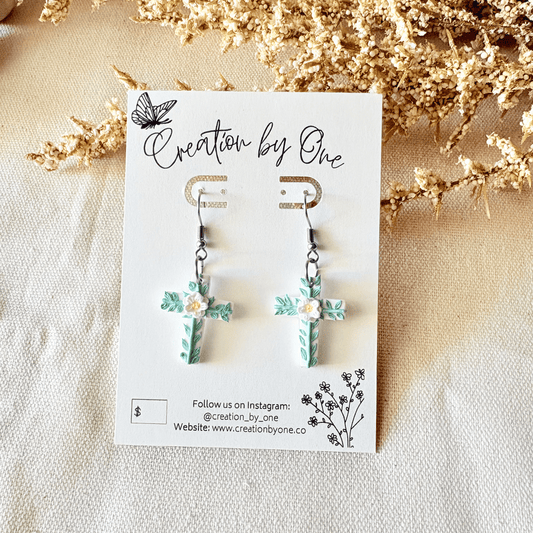 Earrings on a 'Creation by One' branded card with decorative elements.