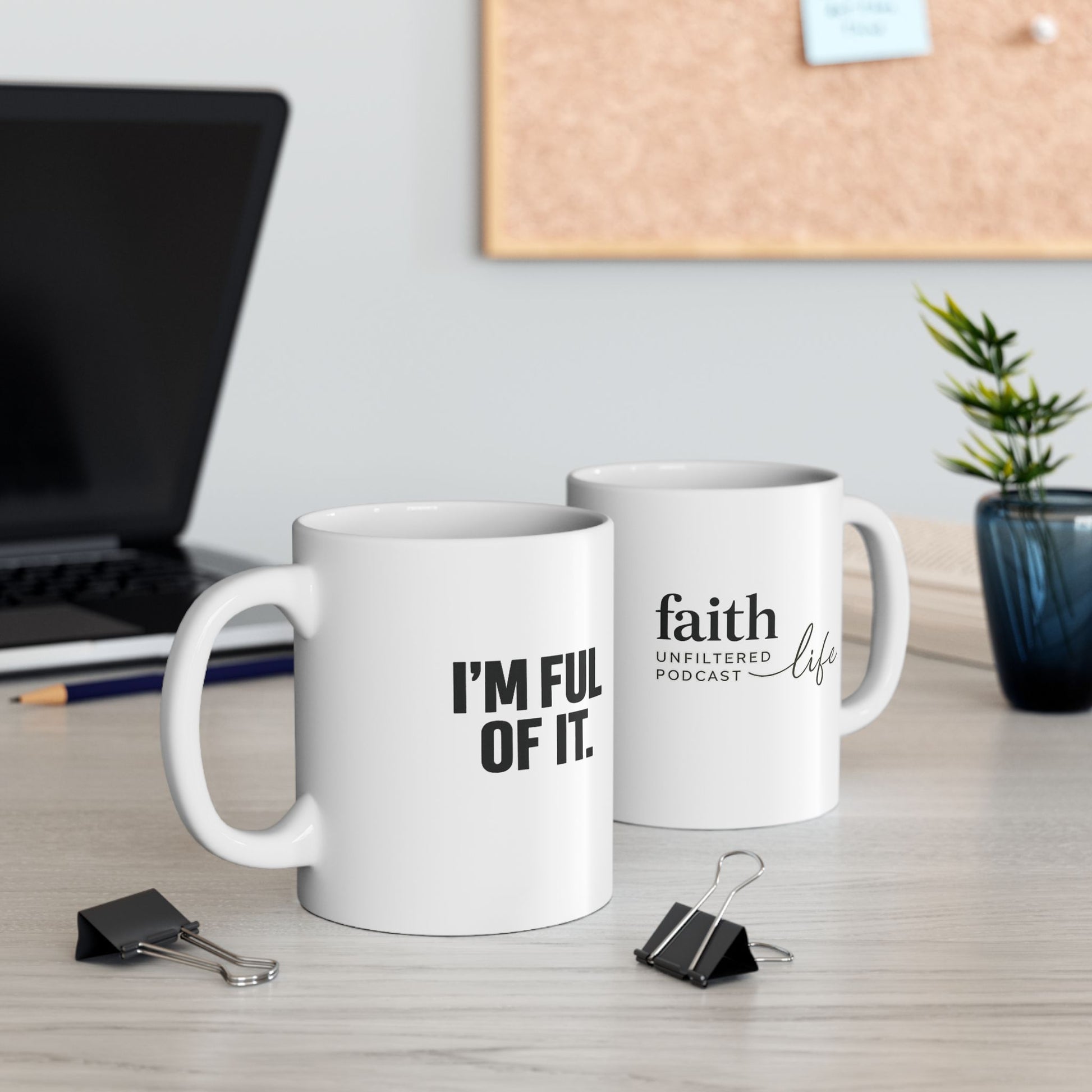 Two white mugs with text on a desk with office items