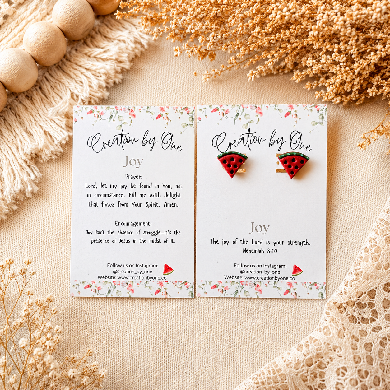 Watermelon-themed earrings on branded cards with decorative elements on a beige surface.