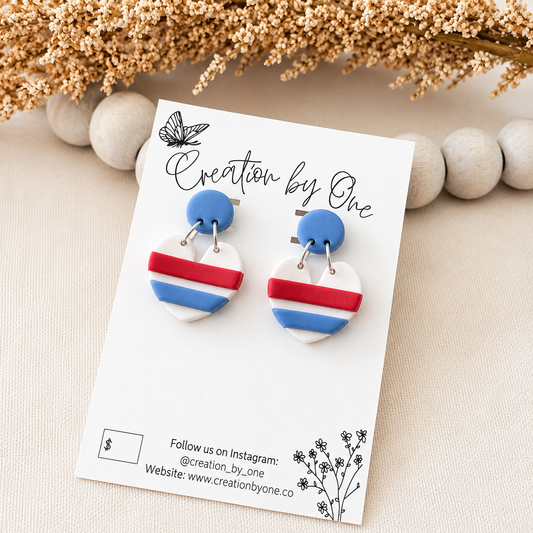 Pair of earrings on a 'Creation by One' branded card with decorative elements.