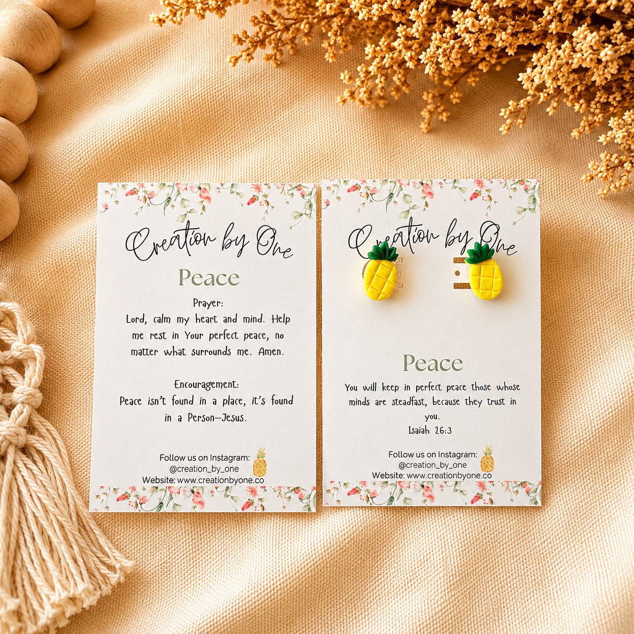 Pair of pineapple earrings on branded cards with text on a beige fabric background