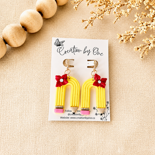 Yellow earrings with red flowers on a white card labeled 'Creation by One' on a beige background.