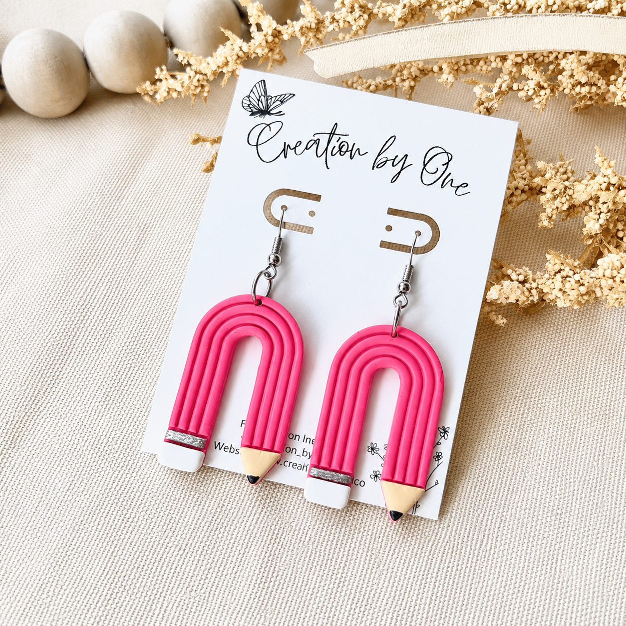 Pink arch-shaped earrings on a card with decorative elements