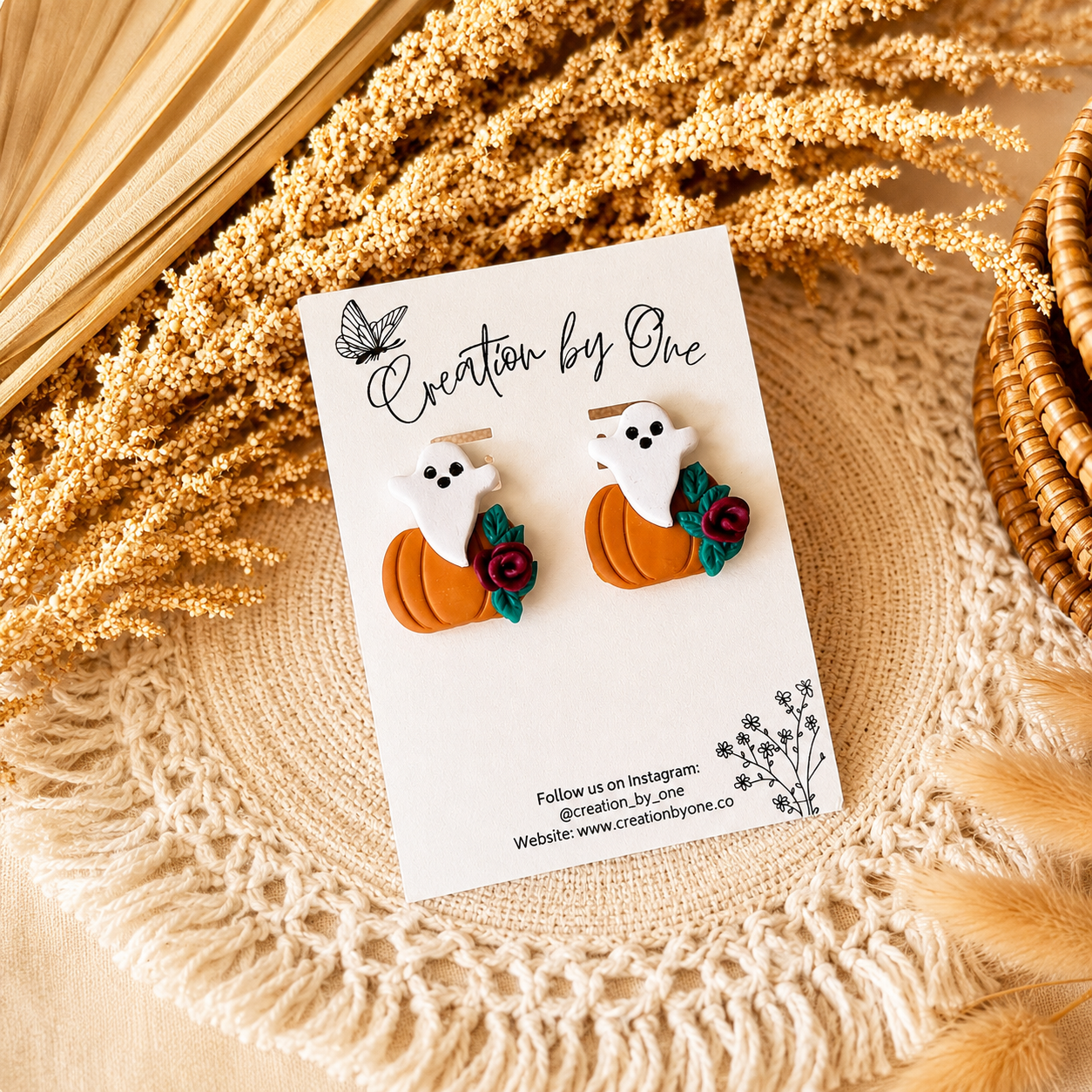 Pair of ghost and pumpkin earrings on a branded card with decorative elements.