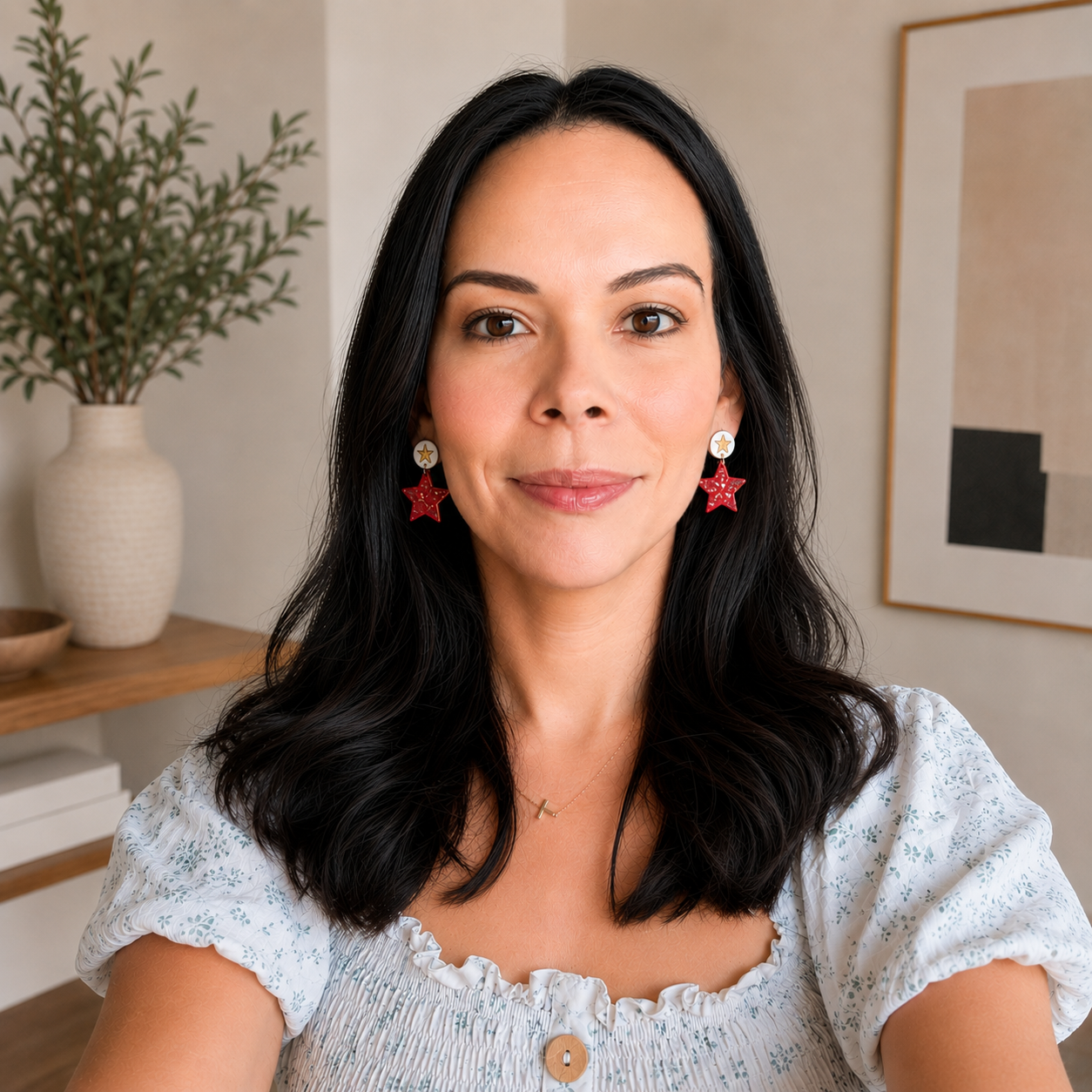 Woman with black hair and red earrings smiling indoors