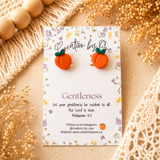 Pumpkin-shaped earrings on a card with decorative elements on a textured surface