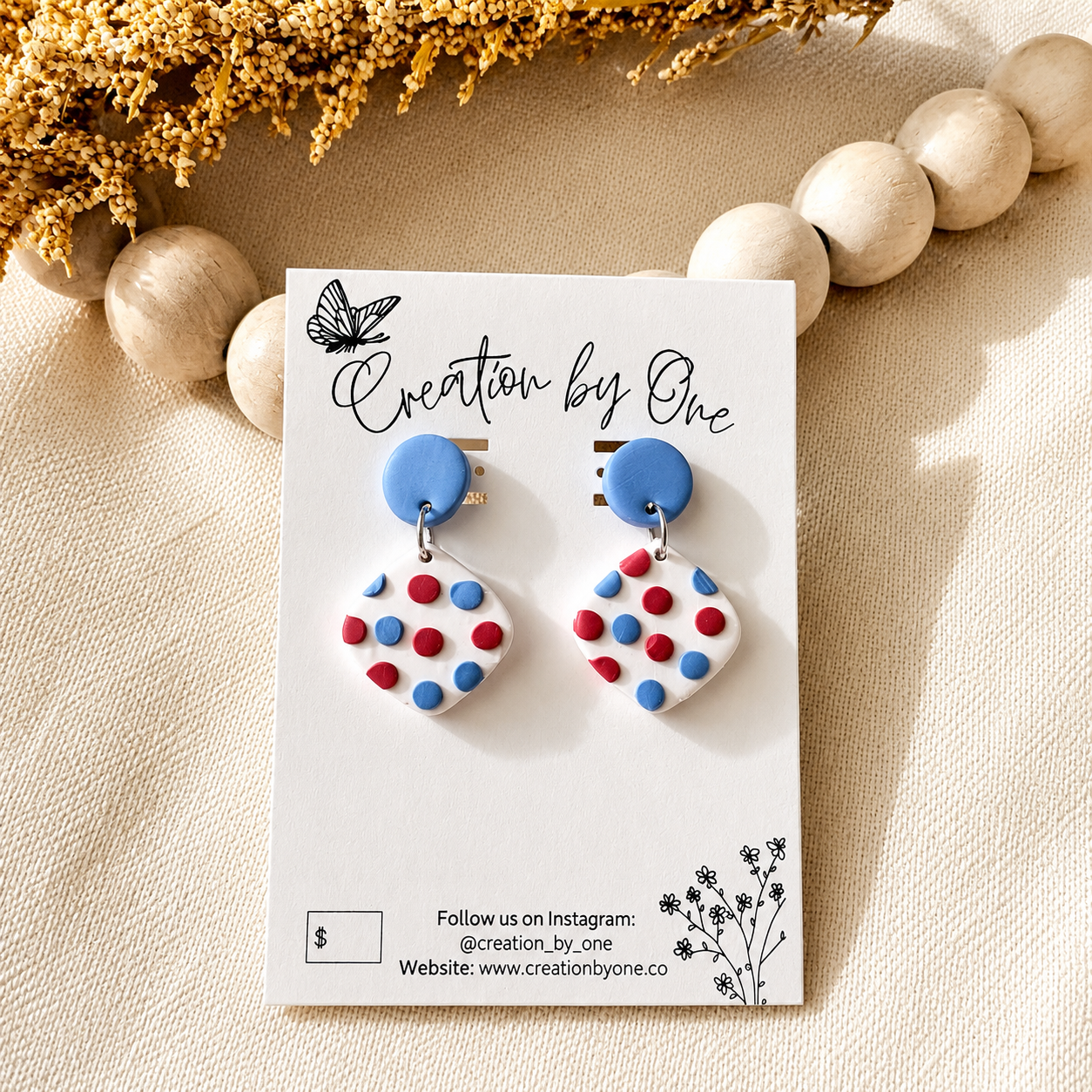 Polka dot earrings on a 'Creation by One' branded card with decorative elements.