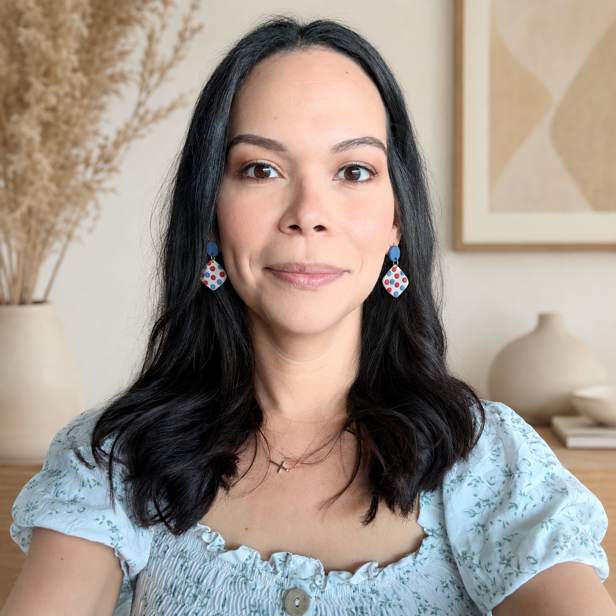 Woman wearing colorful earrings in a neutral indoor setting