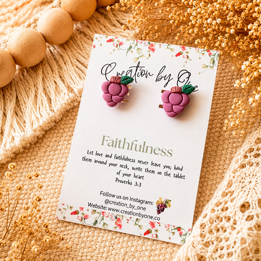 Purple earrings on a 'Creation by Q' card with decorative elements on a textured surface.