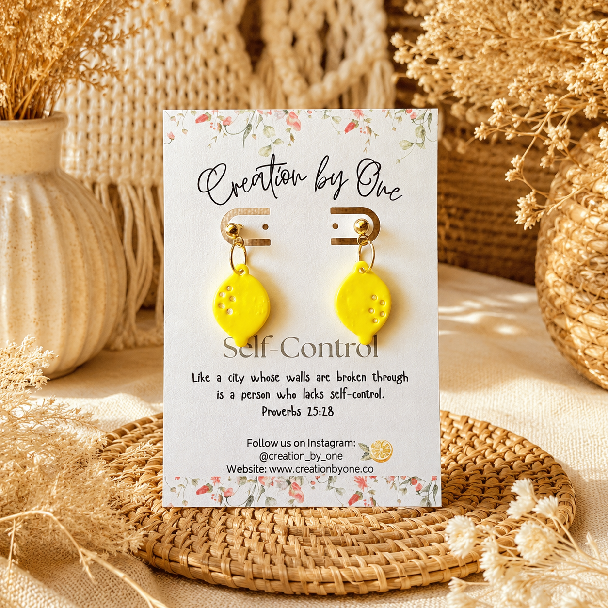 Yellow earrings on a 'Creation by One' branded card with decorative background